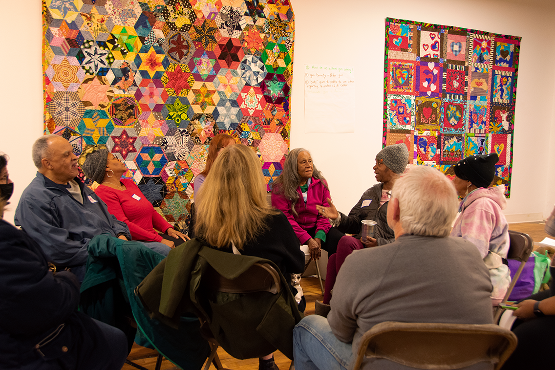 A diverse group of Collinwood residents discuss street violence during a quilt show in the gallery of Praxis Fiber Workshop on Waterloo Road in February, 2023.